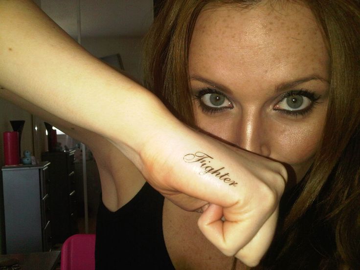 a woman with a tattoo on her arm pointing at the camera