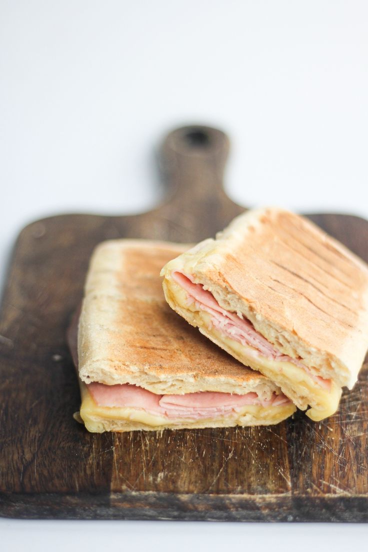 two sandwiches sitting on top of a wooden cutting board