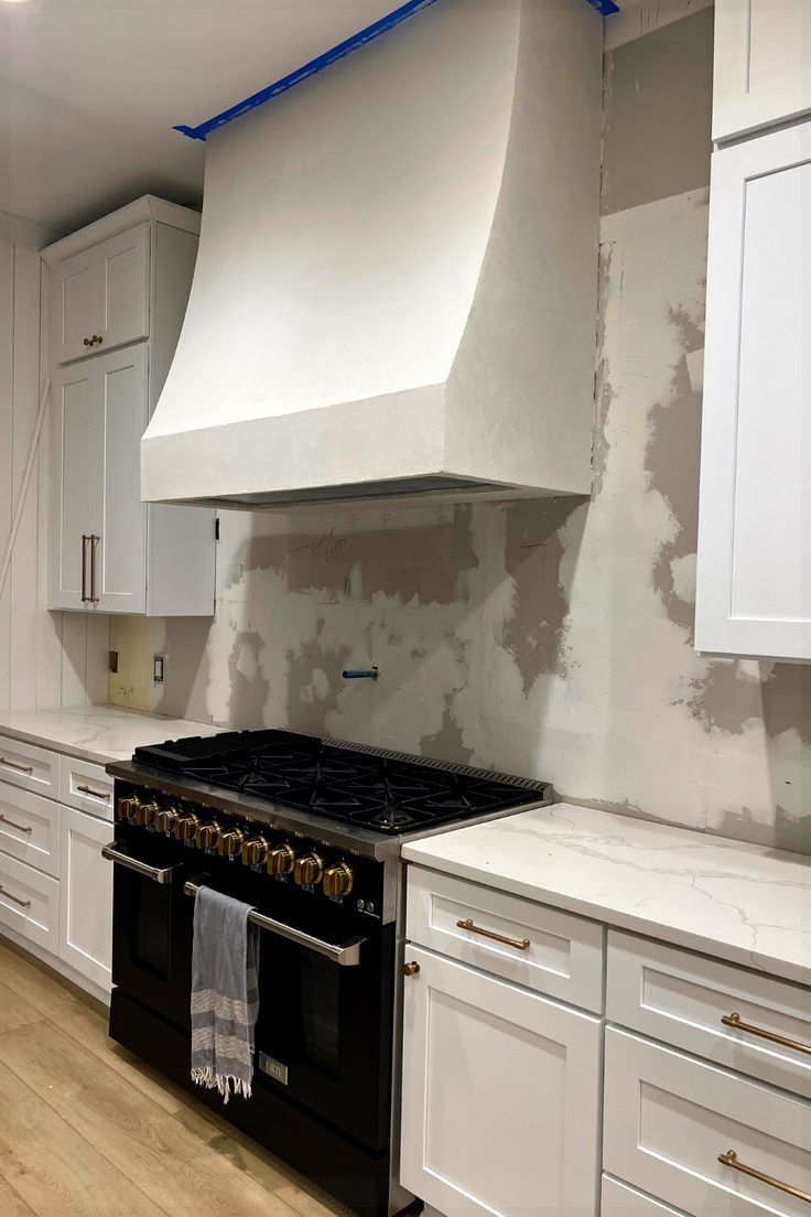 a stove top oven sitting inside of a kitchen next to white cabinets and cupboards