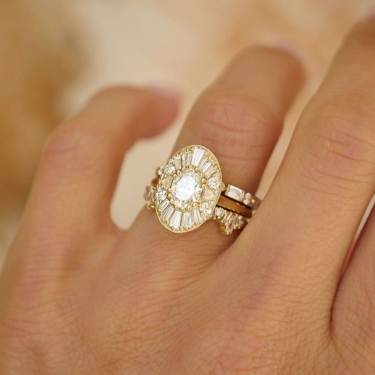 a woman's hand holding a ring with an oval shaped diamond in the center