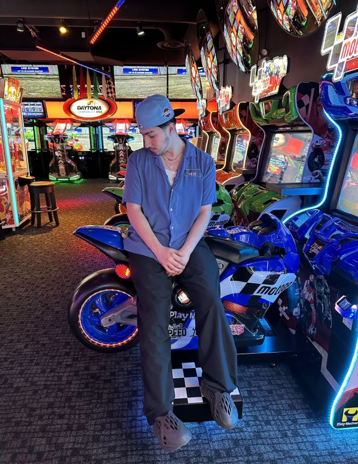 a man sitting on top of a motorcycle in a room filled with video games and arcade machines