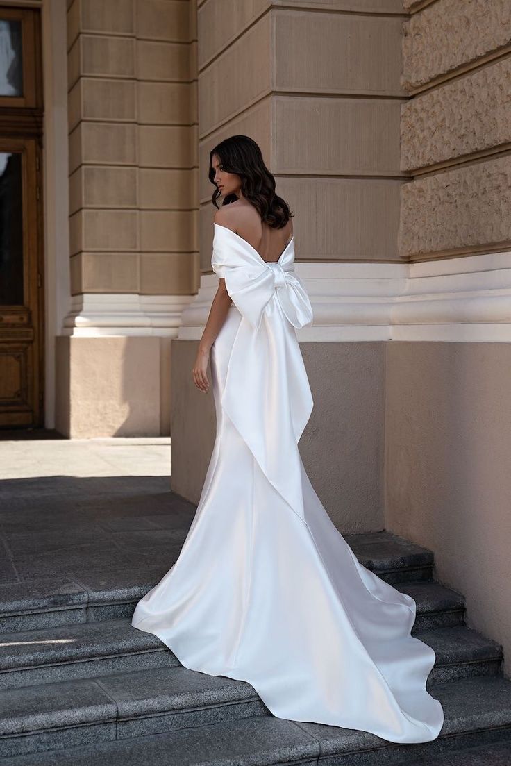 a woman in a white wedding dress standing on steps with her back to the camera