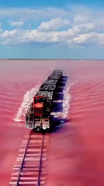 a large boat traveling across a pink lake