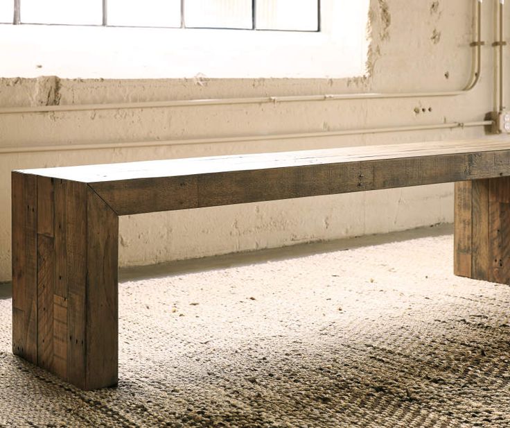 a wooden bench sitting on top of a carpeted floor next to a window in an old building