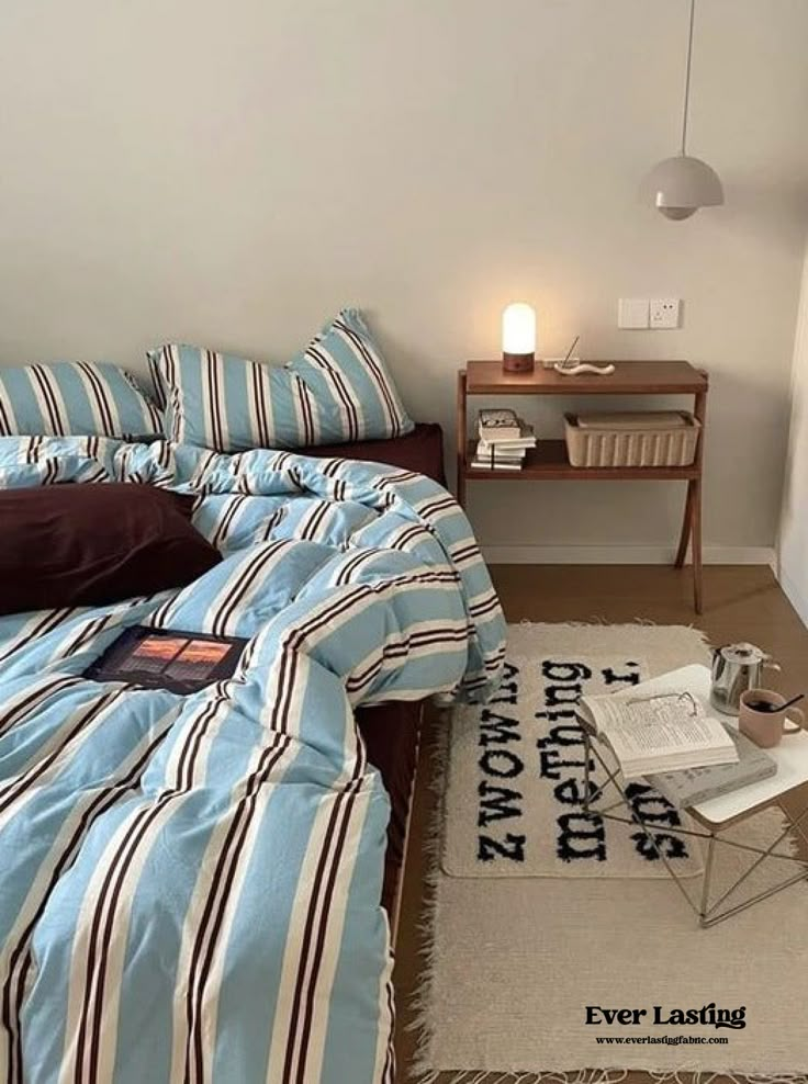 there is a bed with blue and white sheets in the room next to a lamp