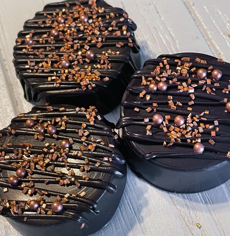 four chocolate covered cakes sitting on top of a white wooden table next to each other