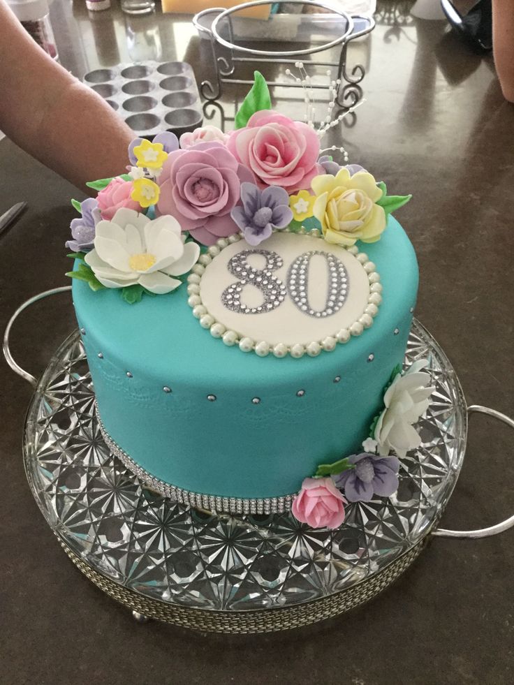 a blue cake with flowers and the number 50 on it is sitting on a glass plate