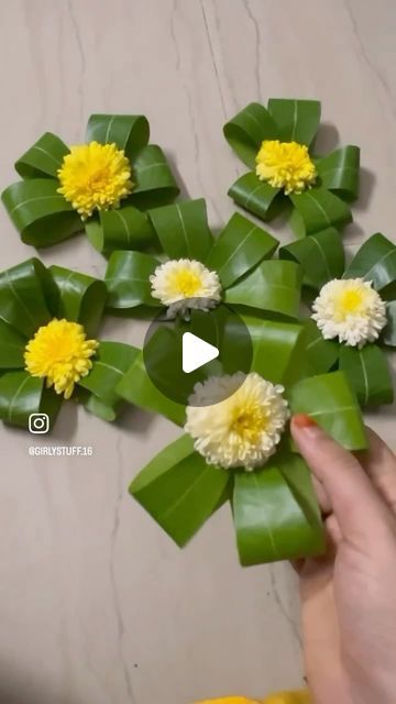 someone is making flowers out of green leaves and yellow flowers in the middle of them