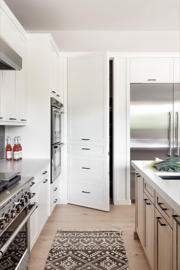 a kitchen with white cabinets and an area rug on the floor in front of the stove