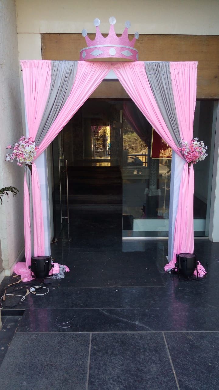 an entrance decorated with pink and grey drapes, flowers and crown on the top