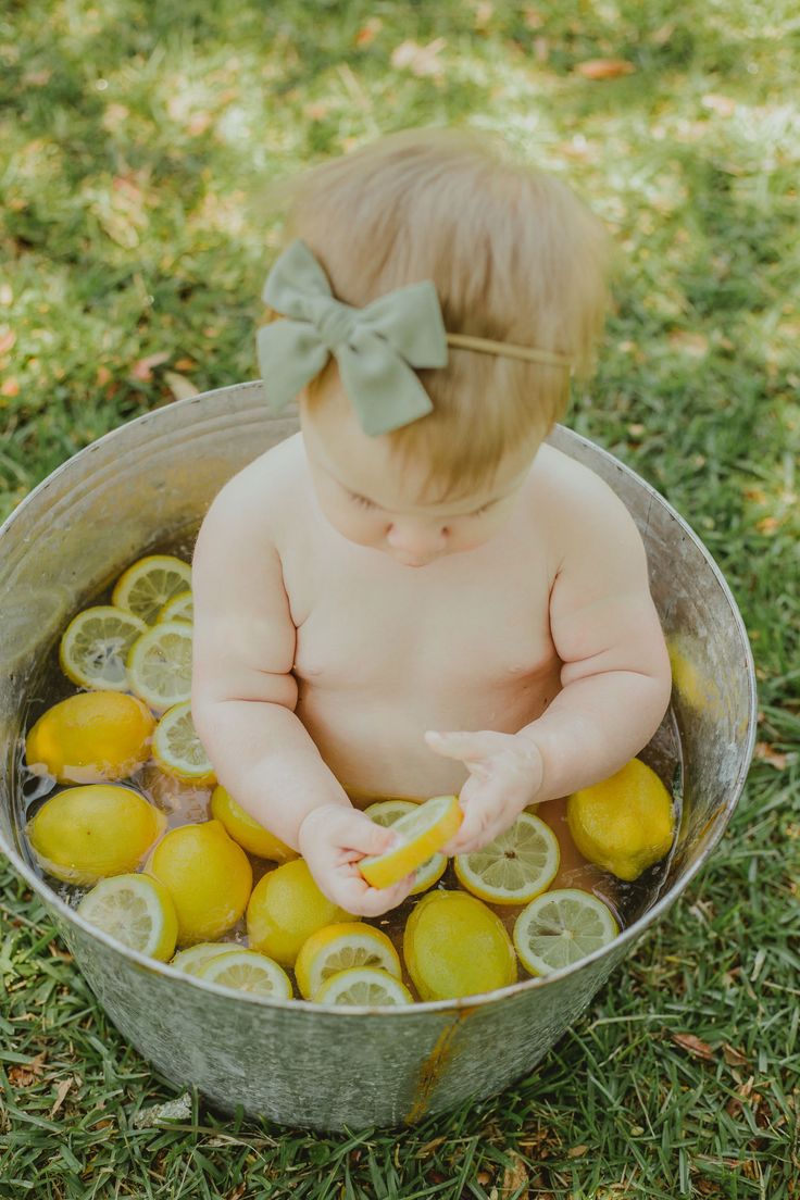 a baby sitting in a bucket filled with lemons