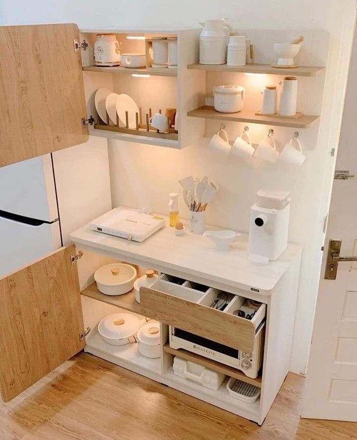 a small kitchen with white appliances and wooden shelves on the wall, in front of a door