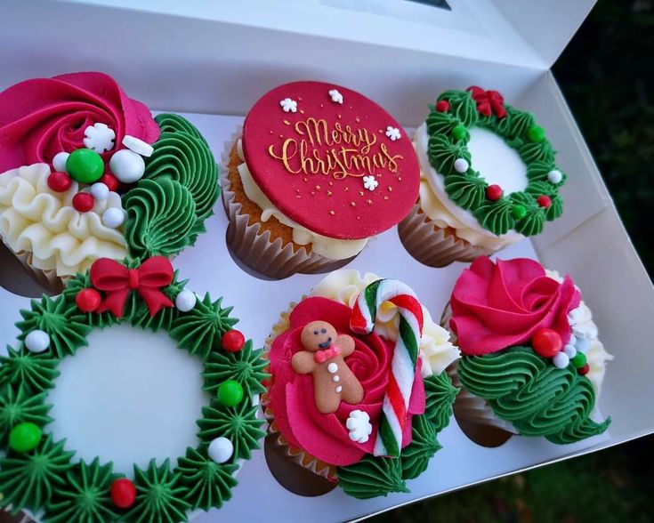 cupcakes decorated with green and red icing are in a box on the table