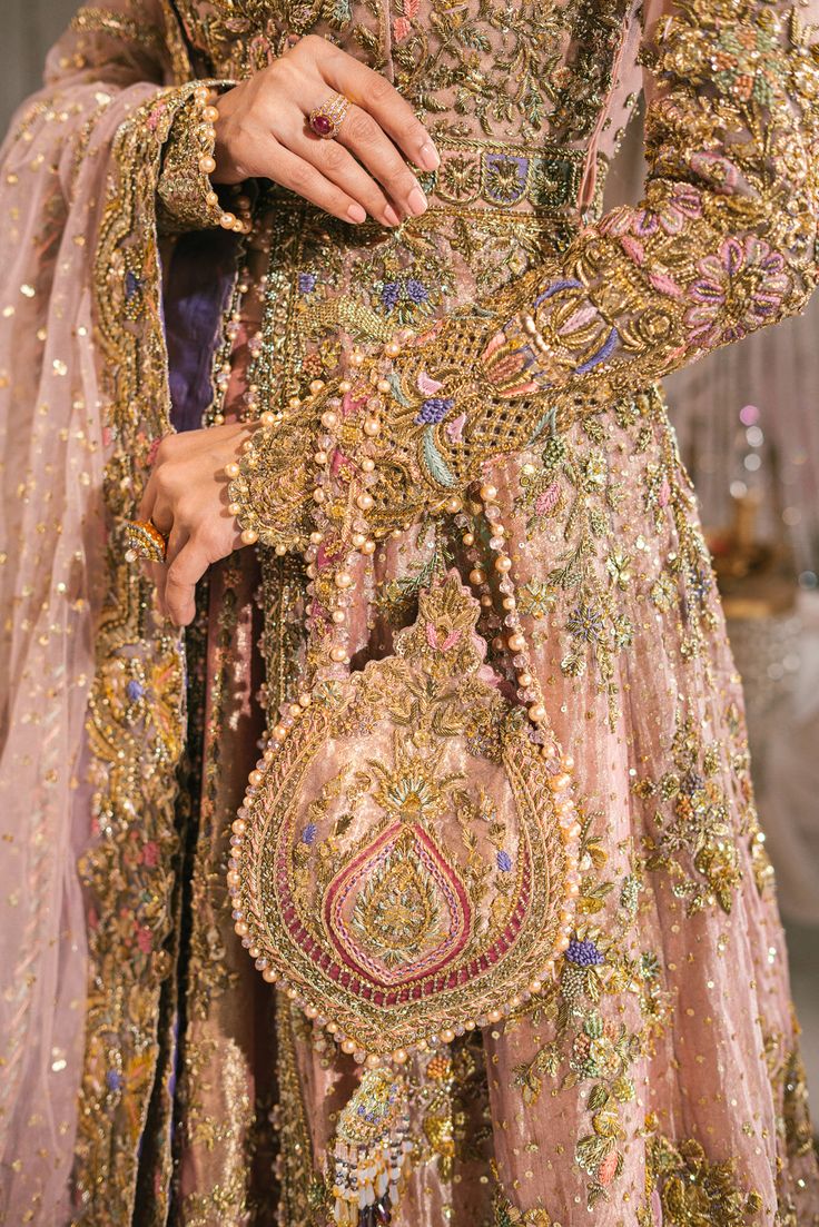 a woman wearing a gold and pink dress with lots of beading on her hands