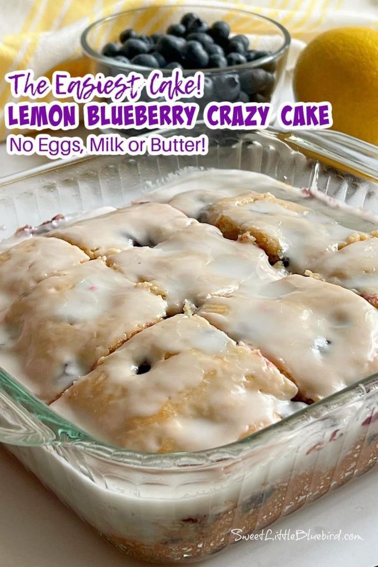 a glass baking dish filled with lemon blueberry crazy cake next to fresh blueberries