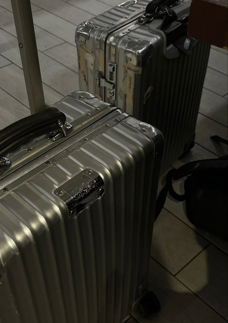 two silver suitcases sitting next to each other on a tiled floor in an airport