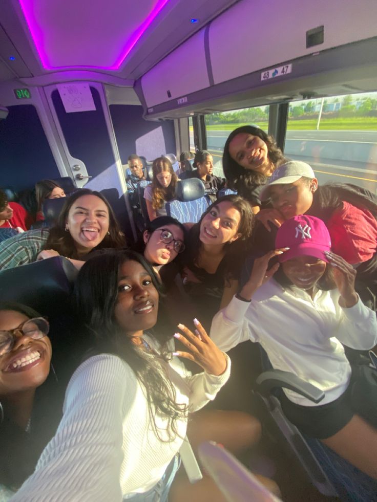 a group of people on a bus posing for the camera with their hands in the air