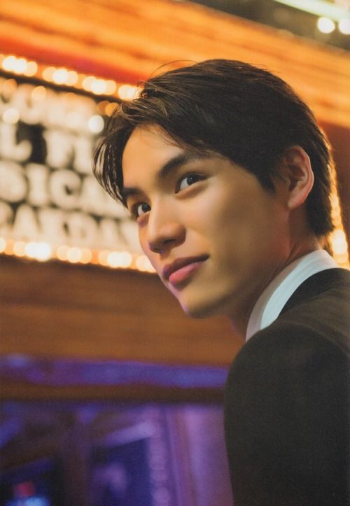 a young man in front of a theater sign with lights on it's side