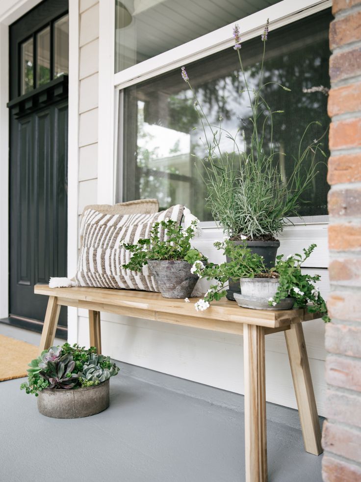 some plants are sitting on a bench in front of a house