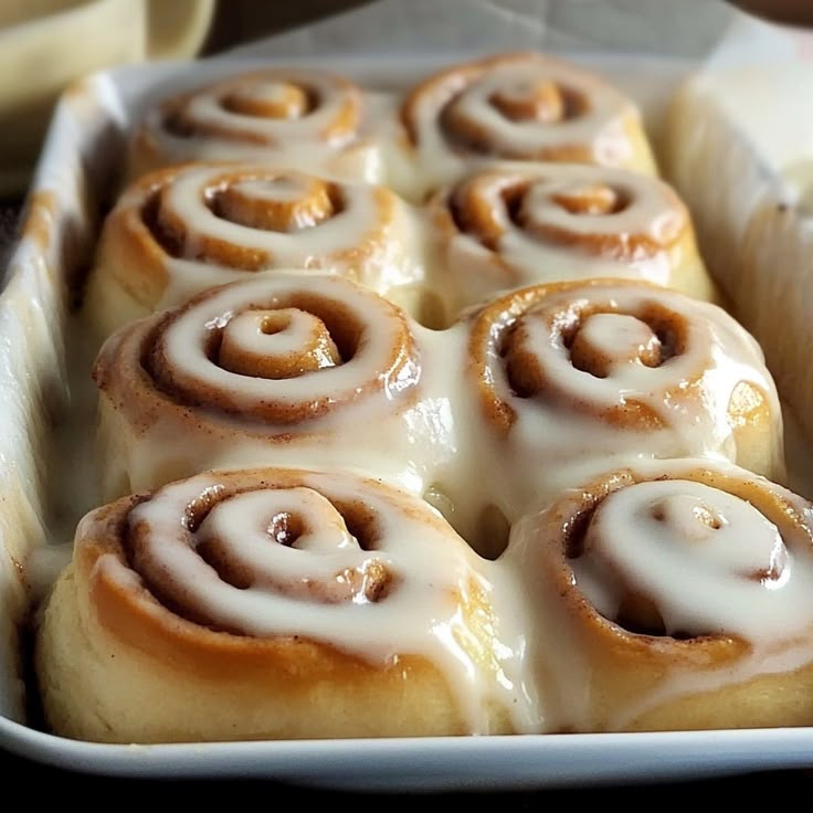 a pan filled with cinnamon rolls covered in icing