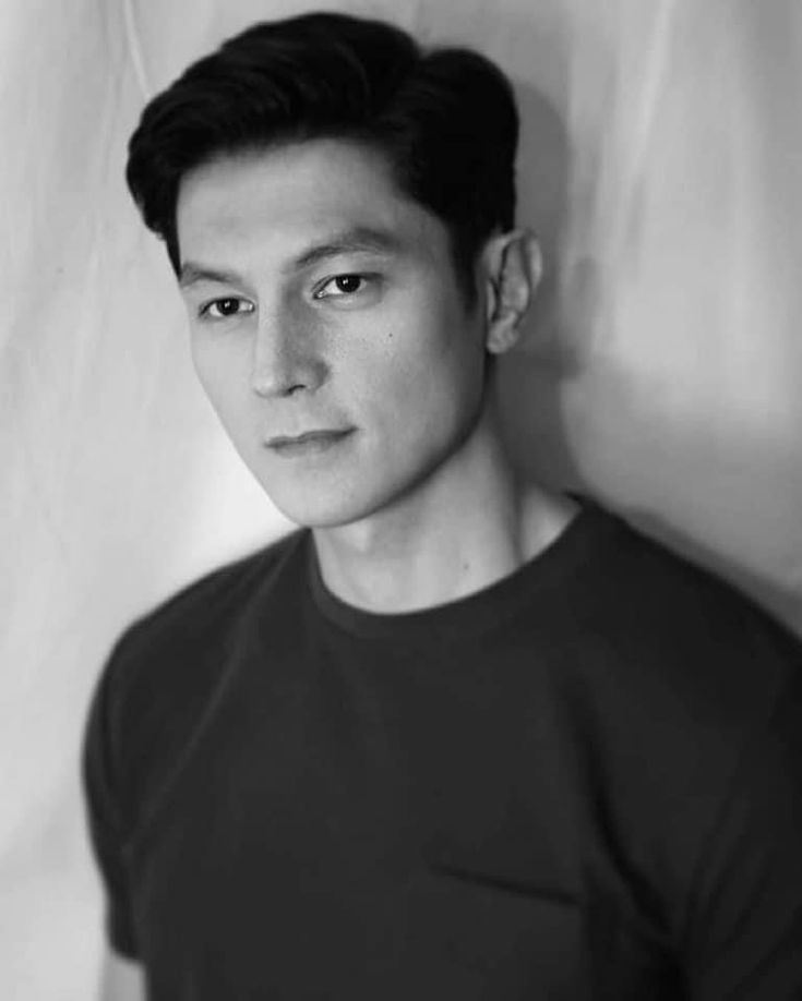 black and white photograph of a young man with short hair wearing a t - shirt