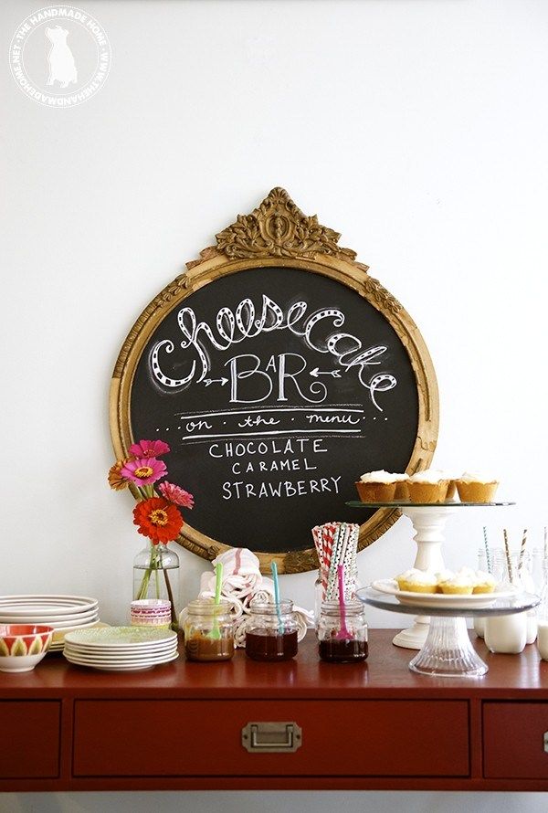 a table topped with lots of desserts next to a chalkboard sign on the wall