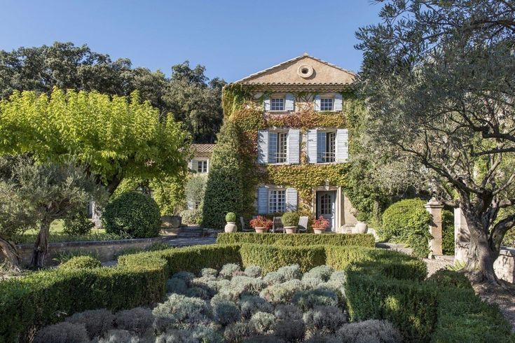 the house is surrounded by hedges and trees