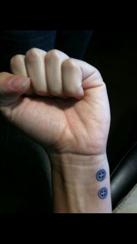 a person with a tattoo on their wrist is holding up the fist that has two blue circles in it