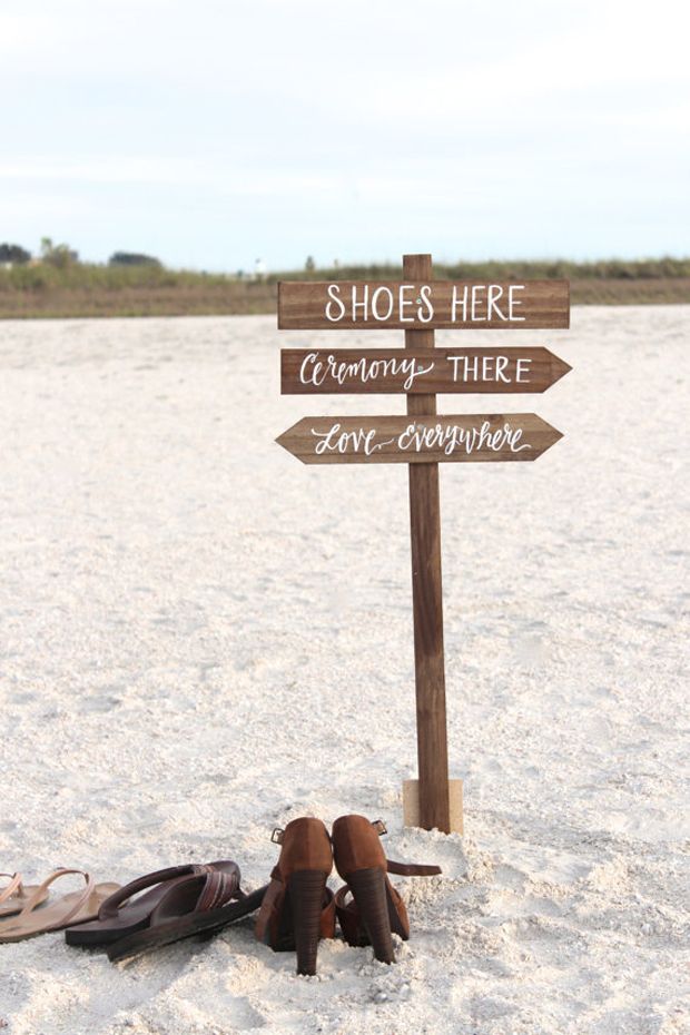 a pair of shoes sitting in the sand next to a sign that says shoes here