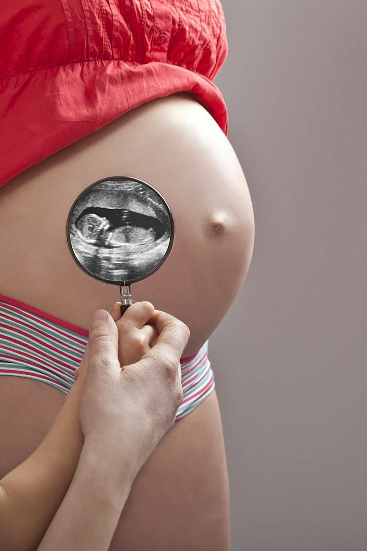 a pregnant woman holding a magnifying glass in front of her belly with the image of a man on it