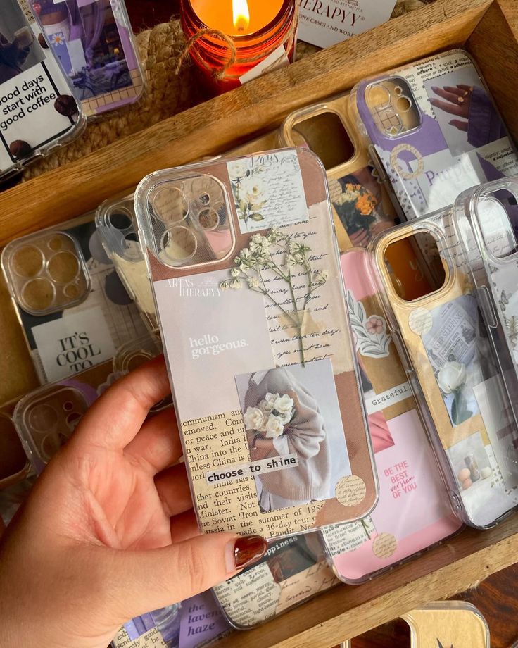 a person holding an iphone case in front of many other items on a wooden table