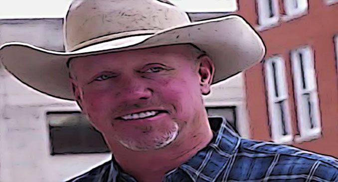 a man wearing a cowboy hat standing in front of a building