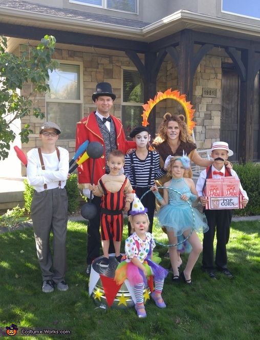 a group of people dressed up in costumes posing for a photo on the lawn outside of a house