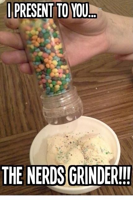 a person holding a jar filled with candy sprinkles on top of a wooden table