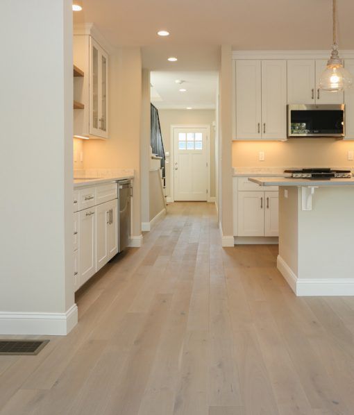 an empty kitchen with white cabinets and wood flooring is pictured in this image from the front door