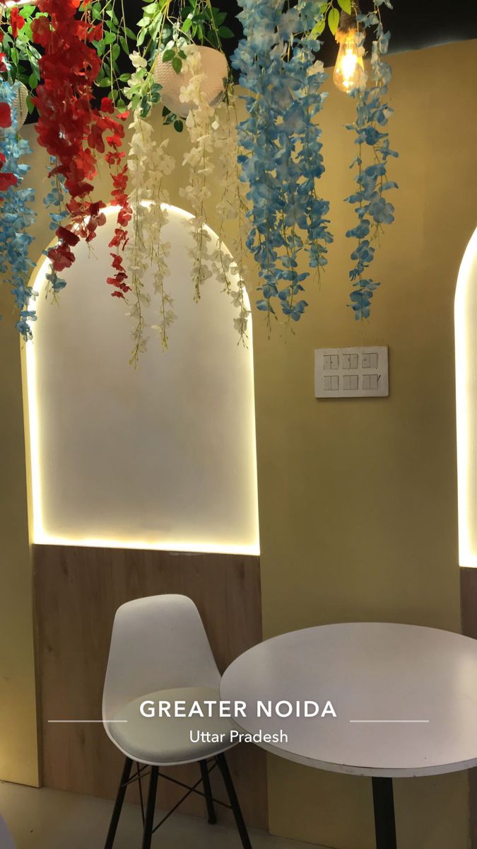 the interior of a restaurant with flowers hanging from the ceiling and chairs in front of it