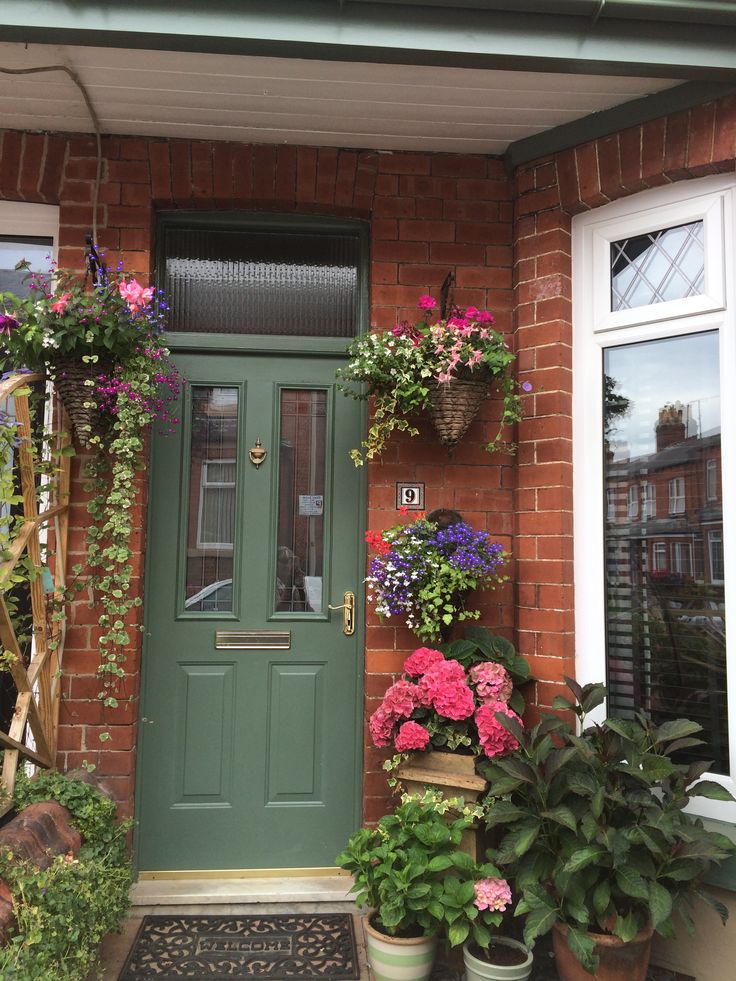 a green front door surrounded by potted plants