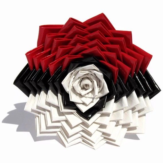 a red and black flower with white petals on it's side, sitting in front of a white background