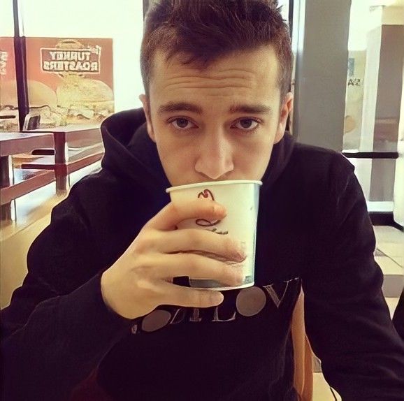 a man sitting at a table drinking from a cup