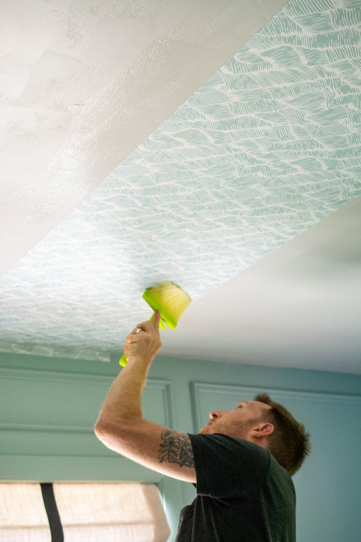 a man is painting the ceiling in his kitchen with green and white paint on it