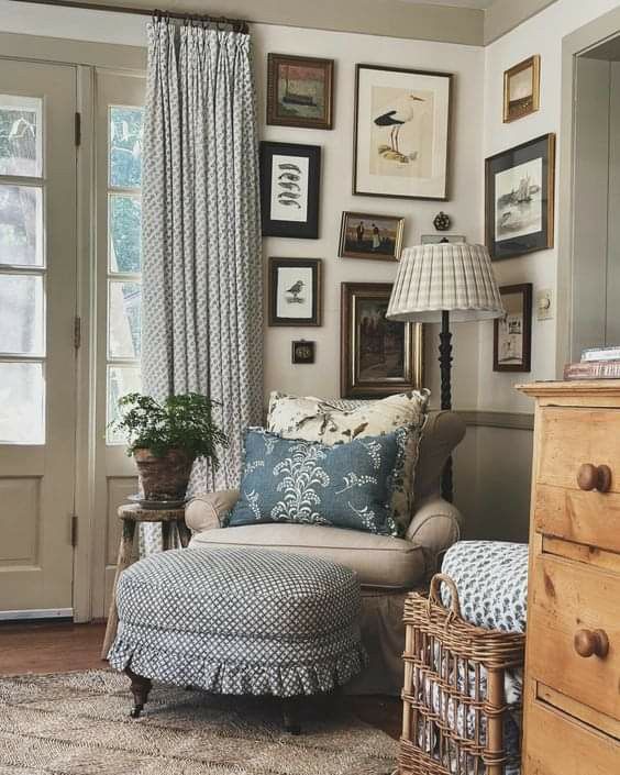 a living room with pictures on the wall and a chair next to a footstool