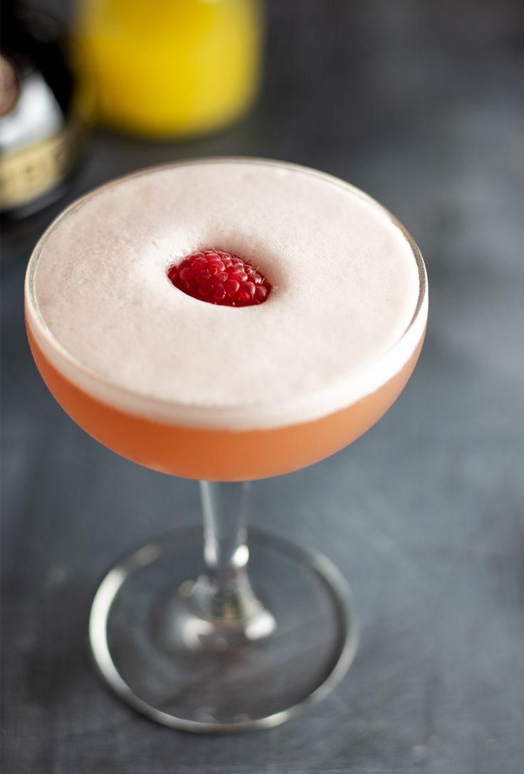 a cocktail with a raspberry garnish on the rim