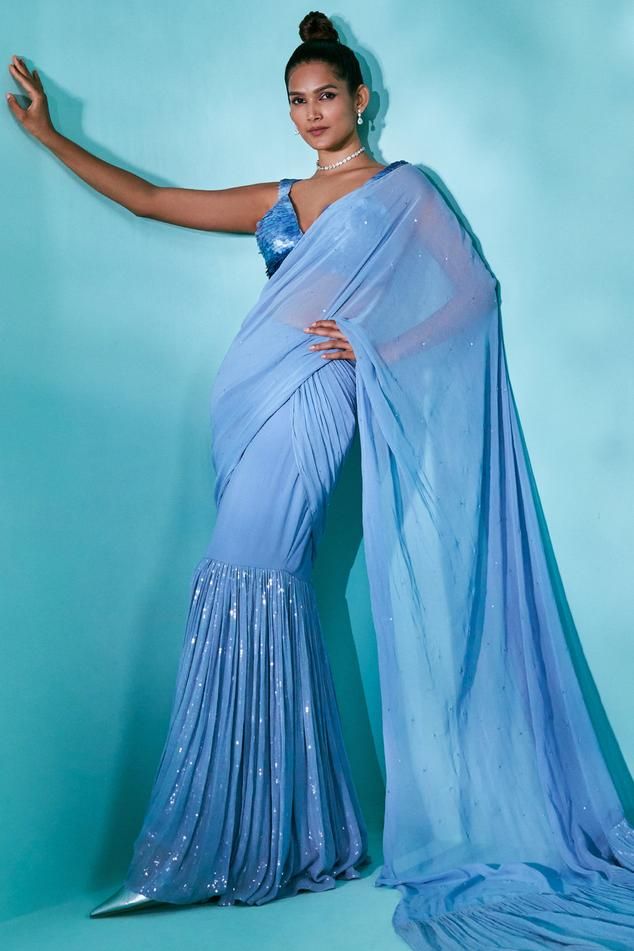 Blue ombre pre-draped saree with layered tiered flare, attached draped pallu and tonal sequin hand embroidery. Paired with padded blouse with all over layered ombre sequin embroidery.
Components: 2
Pattern: Hand Embroidered
Type Of Work: Sequin Work
Neckline: Plunged V Neck
Sleeve Type: Sleeveless
Fabric: Saree: Georgette, Blouse: Swiss Net
Color: Blue
Other Details: 
Length:
Saree: 45 inches
Blouse: 13 inches
Layered pallu border
Deep square back
Blouse Closure: Back hook and eye
Note: The outf Blue Georgette Pre-draped Saree For Evening, Blue Bollywood Draped Blouse Piece, Blue Draped Bollywood Blouse Piece, Blue Floor-length Georgette Blouse Piece, Bollywood Style Draped Blue Blouse Piece, Blue Pre-draped Saree With Draped Sleeves For Party, Blue Pre-draped Saree With Draped Sleeves For Wedding, Blue Pre-draped Saree For Festive Occasions, Blue Pre-draped Saree For Evening