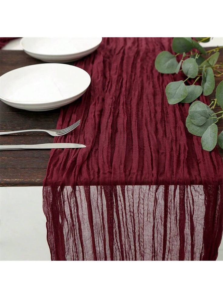 the table is set with white plates and silverware, along with a red cloth draped over it