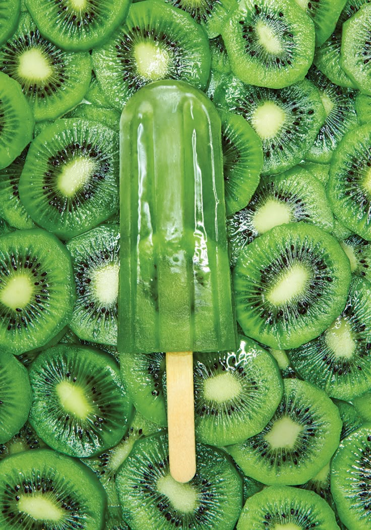 a green popsicle sitting on top of kiwi slices in the middle of it