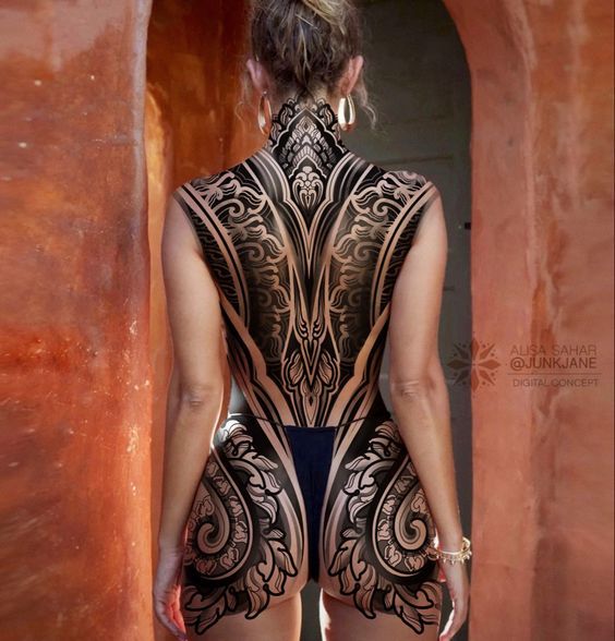 a woman with tattoos on her back standing in front of an archway