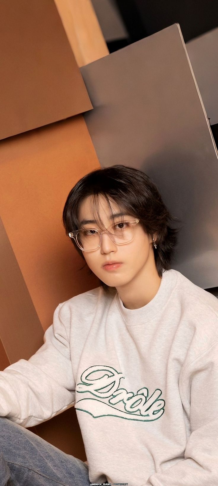 a young man sitting on the ground wearing glasses