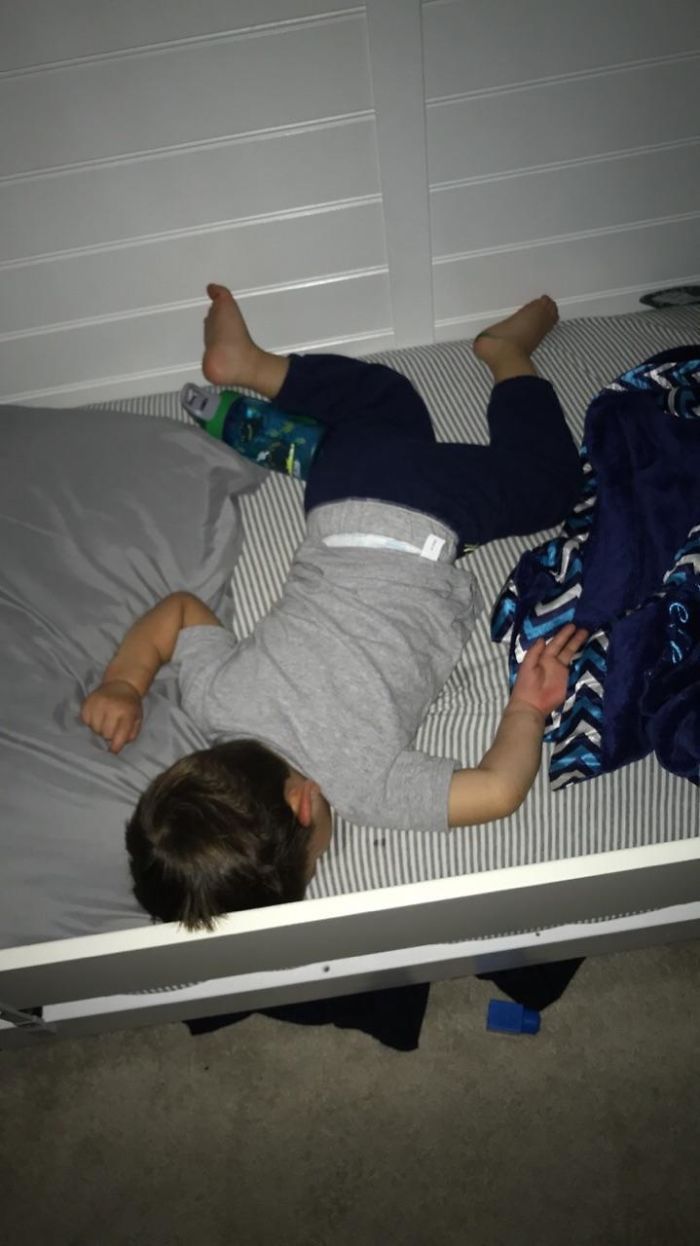 a young boy laying on top of a bed