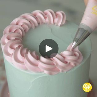 someone is decorating a cake with pink icing and a pipe sticking out of it