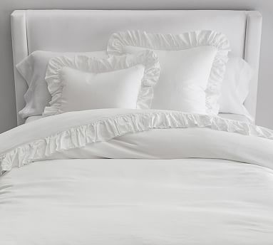 white bedding with ruffles and pillows in a bedroom